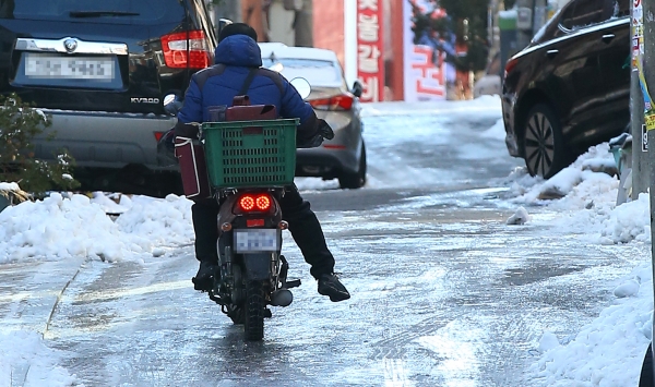 한 음식점 배달원이 오토바이를 타고 빙판길을 오르고 있다. 사진=연합뉴스