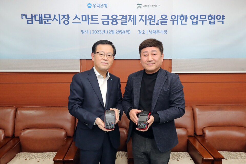 우리은행(은행장 조병규)은 민생금융지원방안 중 자율프로그램의 일환으로 지난 28일 남대문시장 상인회와 ‘상생경영 및 동반성장을 위한 협약’을 체결하고 스마트 결제기기 지원을 통해 남대문시장 스마트 결제 인프라 구축을 지원하기로 했다. 조병규 우리은행장(왼쪽)과 문남엽 상인회 회장이 기념촬영을 하고 있다. 사진=우리은행