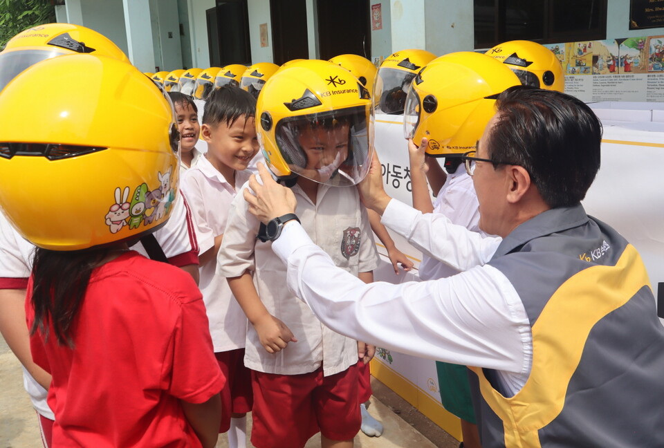 안전모 전달식에 참여한 조정래 KB손해보험 인니법인장이 Sinar Cahaya Kasih 학교 학생들에게 안전모를 씌워주고 있다. 사진=KB손해보험