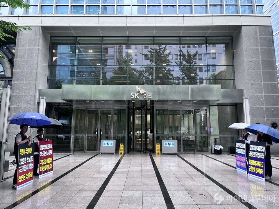 18일 서울시 영등포구 SK증권 본사에서 노동조합원이 폭우 속에서도 점포 통폐합에 대해 피켓을 들고 시위하고 있다.  사진=조송원 기자