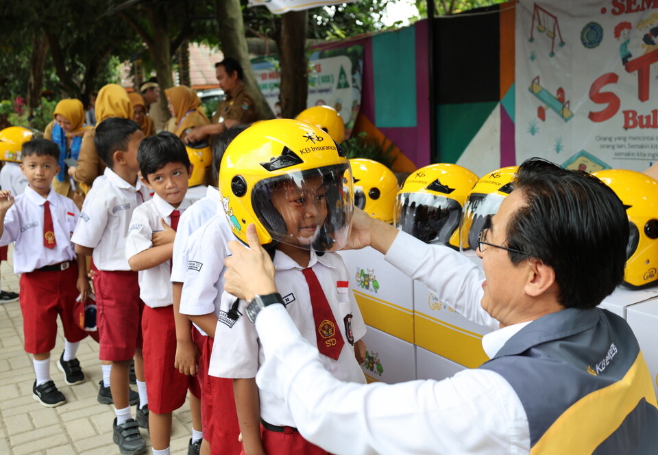 조정래 KB손해보험 인니법인장이 학생들에게 안전모를 씌워주고 있다. 사진=KB손해보험