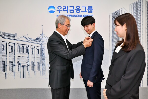 임종룡 우리금융그룹 회장(왼쪽)이 이번에 우리금융그룹으로 편입된 동양생명·ABL생명 직원에게 디지털 선도의 의미가 담긴 새로운 그룹 보조휘장을 달아주고 있다. 사진=우리금융그룹