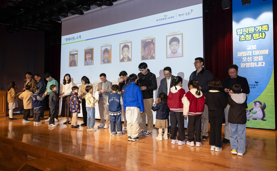 ‘교보 패밀리 데이’에 참여한 임직원이 지난달 27일 서울 종로구 교보생명 본사에서 자녀의 목에 명예사원증을 걸어주고 있다. 사진=교보생명